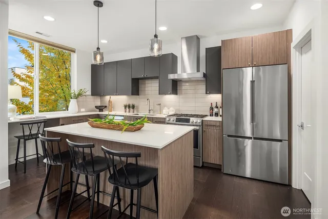 a kitchen with stainless steel appliances granite countertop a refrigerator a sink a stove a dining table and chairs