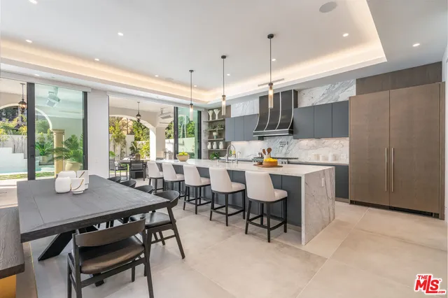 a open dining room with stainless steel appliances kitchen island granite countertop a table chairs and a refrigerator
