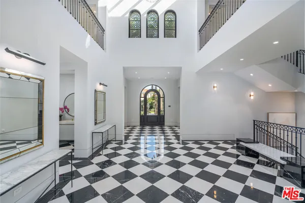 a living room with a black white checkered floor with a gaming machine and glass windows