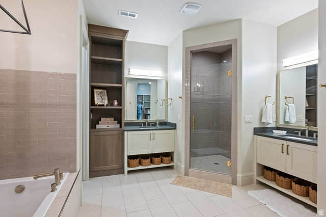 3 Carriagewood Cove, Unit 1088 Sandy, UT 84092 - Photo 59 of 79 Spacious bathroom featuring a frameless glass shower enclosure, a built-in soaking tub, dual vanities with integrated sinks, custom cabinetry, and large format tile flooring