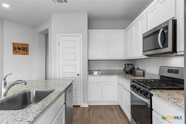 a kitchen with stainless steel appliances granite countertop a sink stove and microwave
