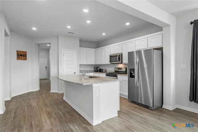 a kitchen with refrigerator cabinets and wooden floor