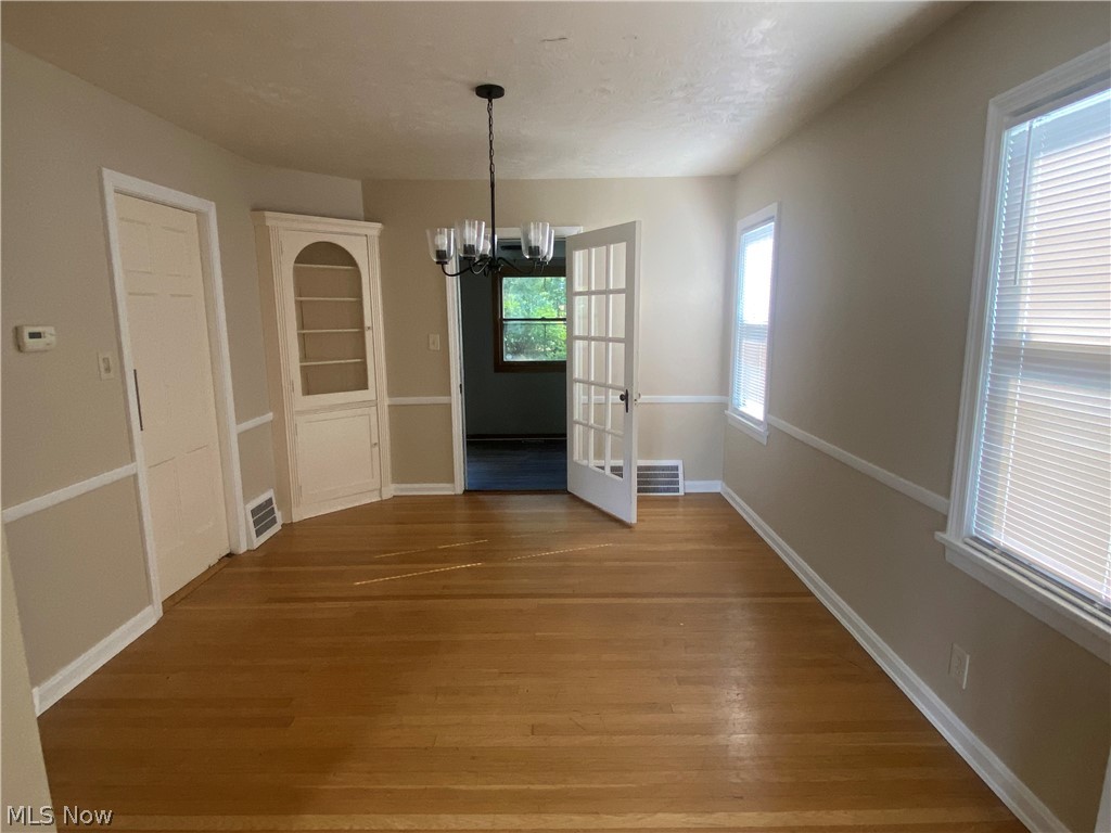 4218 Silsby Road University Heights, OH 44118 - Photo 10 of 27 Hardwood flooring, white wainscoting, built-in display cabinet, French doors, and ceiling-mounted light fixture