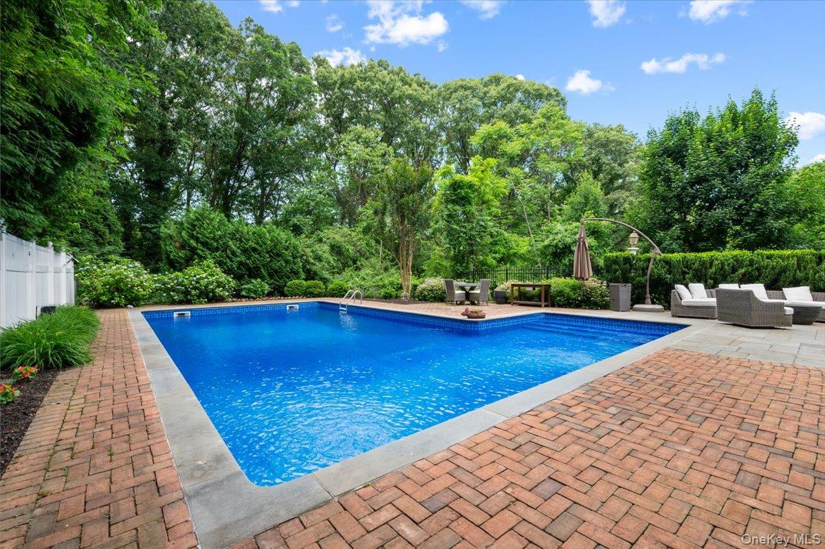 5 Fox Hunt Court Cold Spring Harbor, NY 11724 - Photo 29 of 42 In-ground swimming pool with a surrounding brick paver patio, stone coping, and mature perimeter landscaping