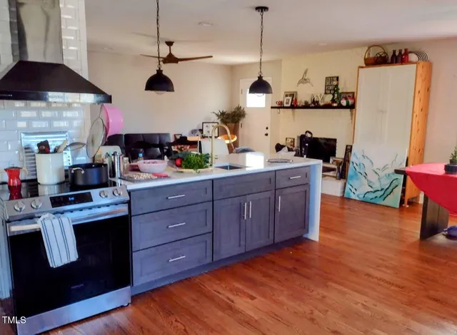 a kitchen with stainless steel appliances granite countertop a sink a stove a refrigerator and wooden floors