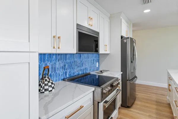 a kitchen with stainless steel appliances kitchen island granite countertop a dining table chairs and a refrigerator