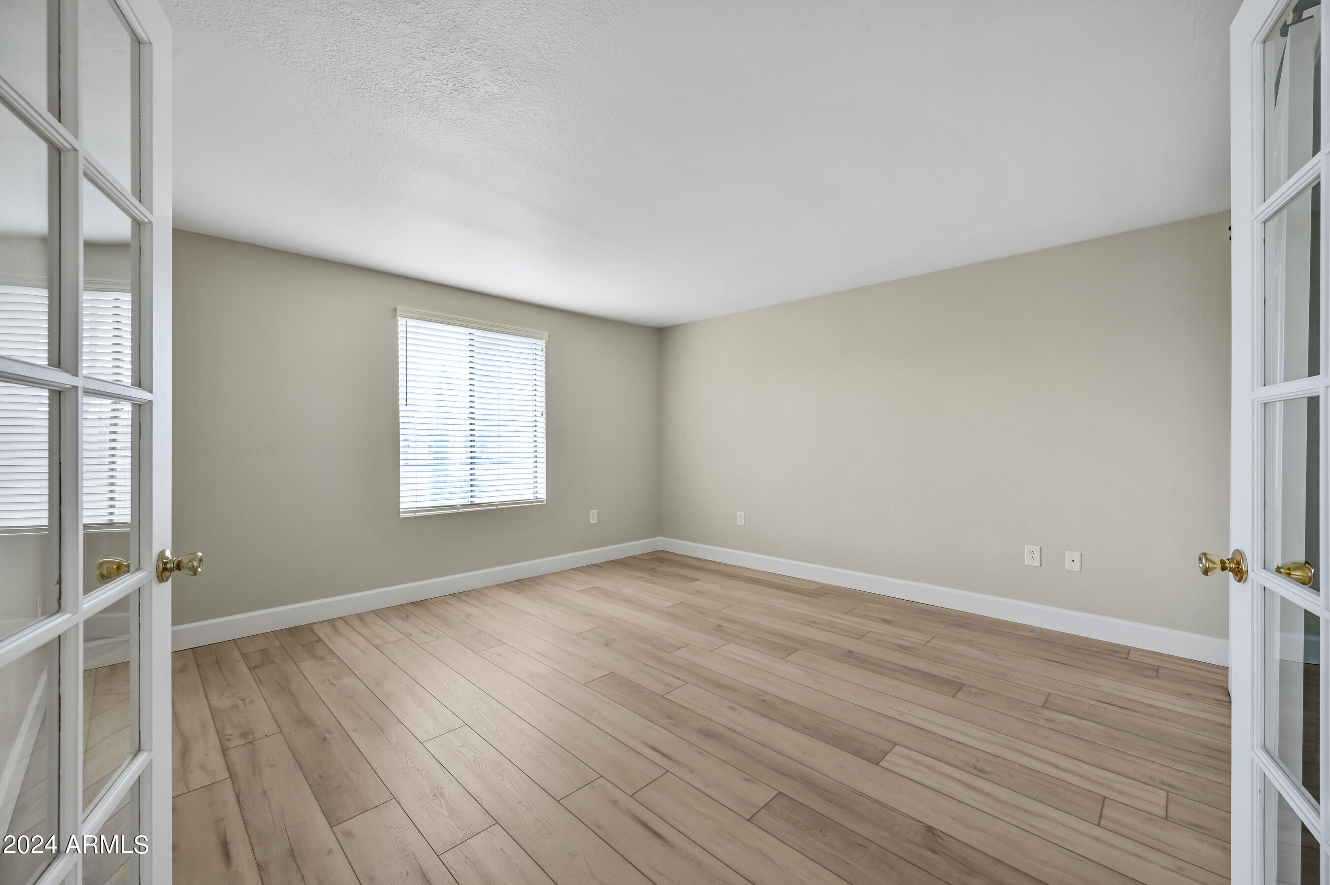 17404 North 99th Avenue, Unit 338 Sun City, AZ 85373 - Photo 25 of 27 an empty room with wooden floor and windows