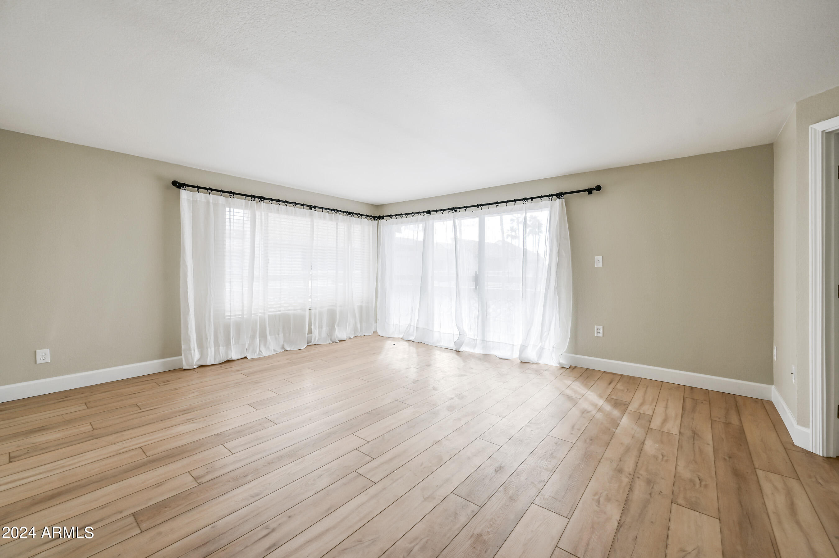 17404 North 99th Avenue, Unit 338 Sun City, AZ 85373 - Photo 5 of 27 a view of an empty room with wooden floor and a window