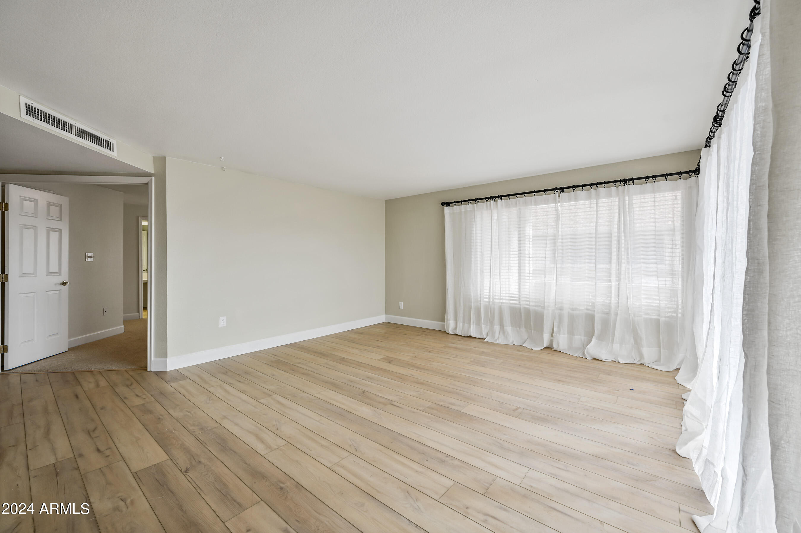 17404 North 99th Avenue, Unit 338 Sun City, AZ 85373 - Photo 6 of 27 a view of an empty room with wooden floor and a window