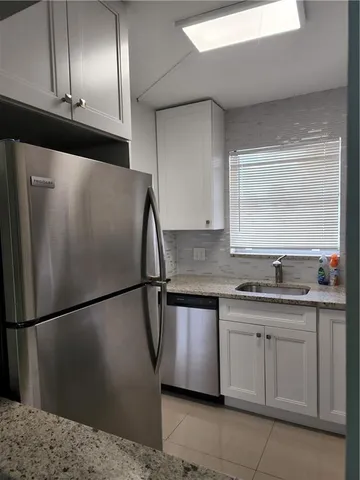 a kitchen with a sink a refrigerator and cabinets