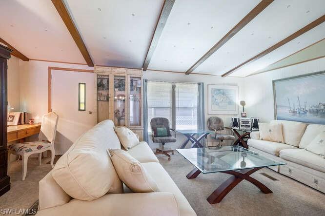 131 Grassy Key Lane, Unit 44 Naples, FL 34114 - Photo 11 of 30 Living room with vaulted ceiling with beams and carpet floors