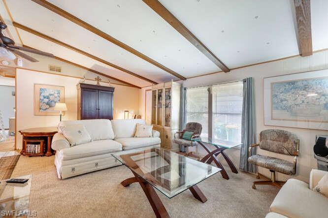 131 Grassy Key Lane, Unit 44 Naples, FL 34114 - Photo 12 of 30 Living room with vaulted ceiling with beams, ceiling fan, and carpet floors