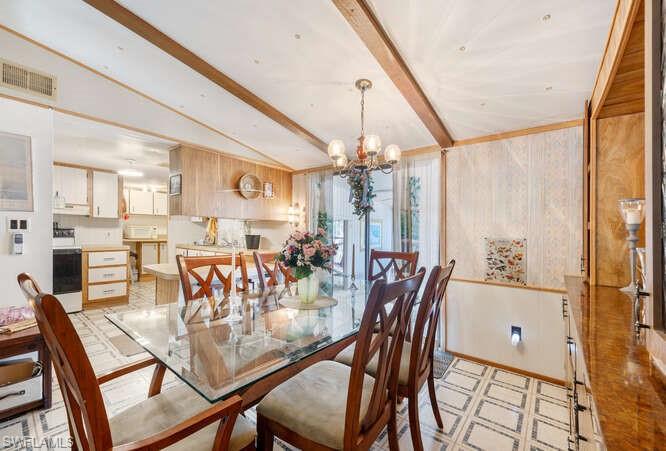 131 Grassy Key Lane, Unit 44 Naples, FL 34114 - Photo 21 of 30 Dining space with vaulted ceiling with beams, wooden walls, and an inviting chandelier