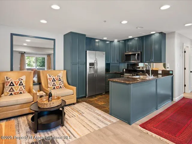a kitchen with stainless steel appliances kitchen island granite countertop a refrigerator and a sink