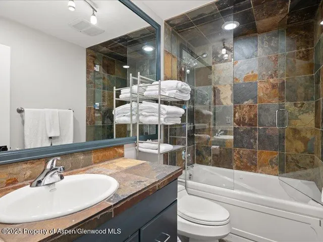 a bathroom with a granite countertop sink toilet and shower