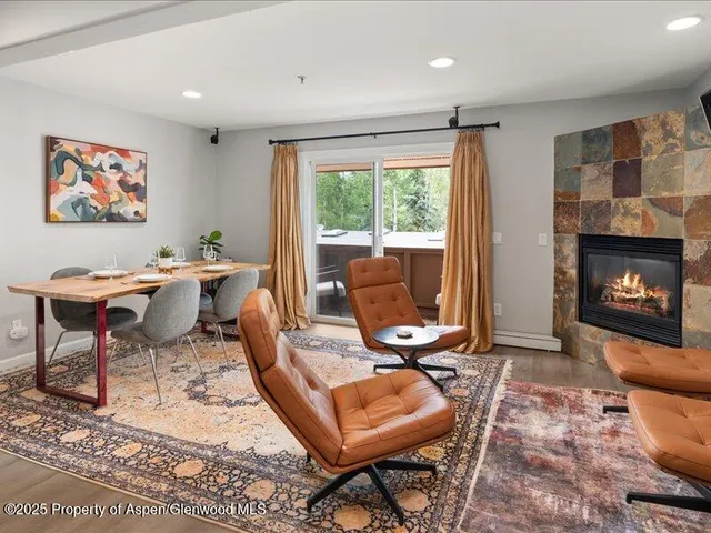 a living room with furniture a fireplace and a floor to ceiling window