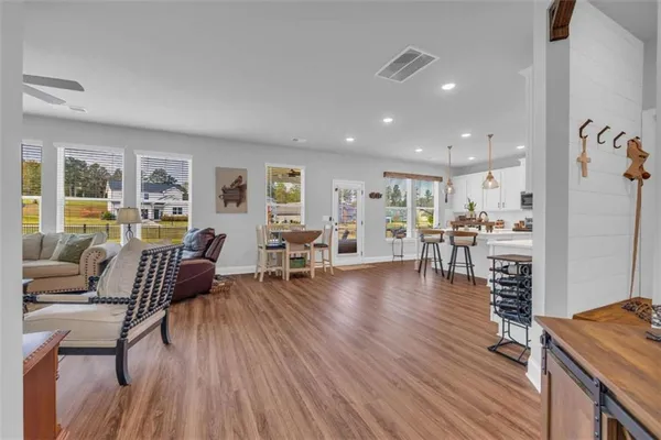 a kitchen with stainless steel appliances kitchen island granite countertop a refrigerator a stove top oven and a dining table with wooden floor