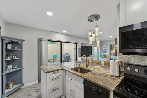 a kitchen with a stove a sink and a flat screen tv