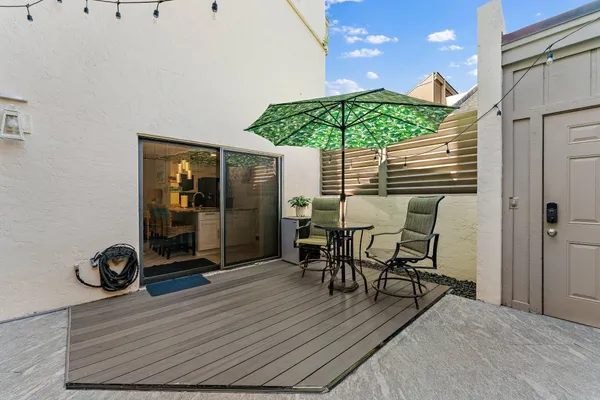 a view of a patio with table and chairs under an umbrella with wooden floor