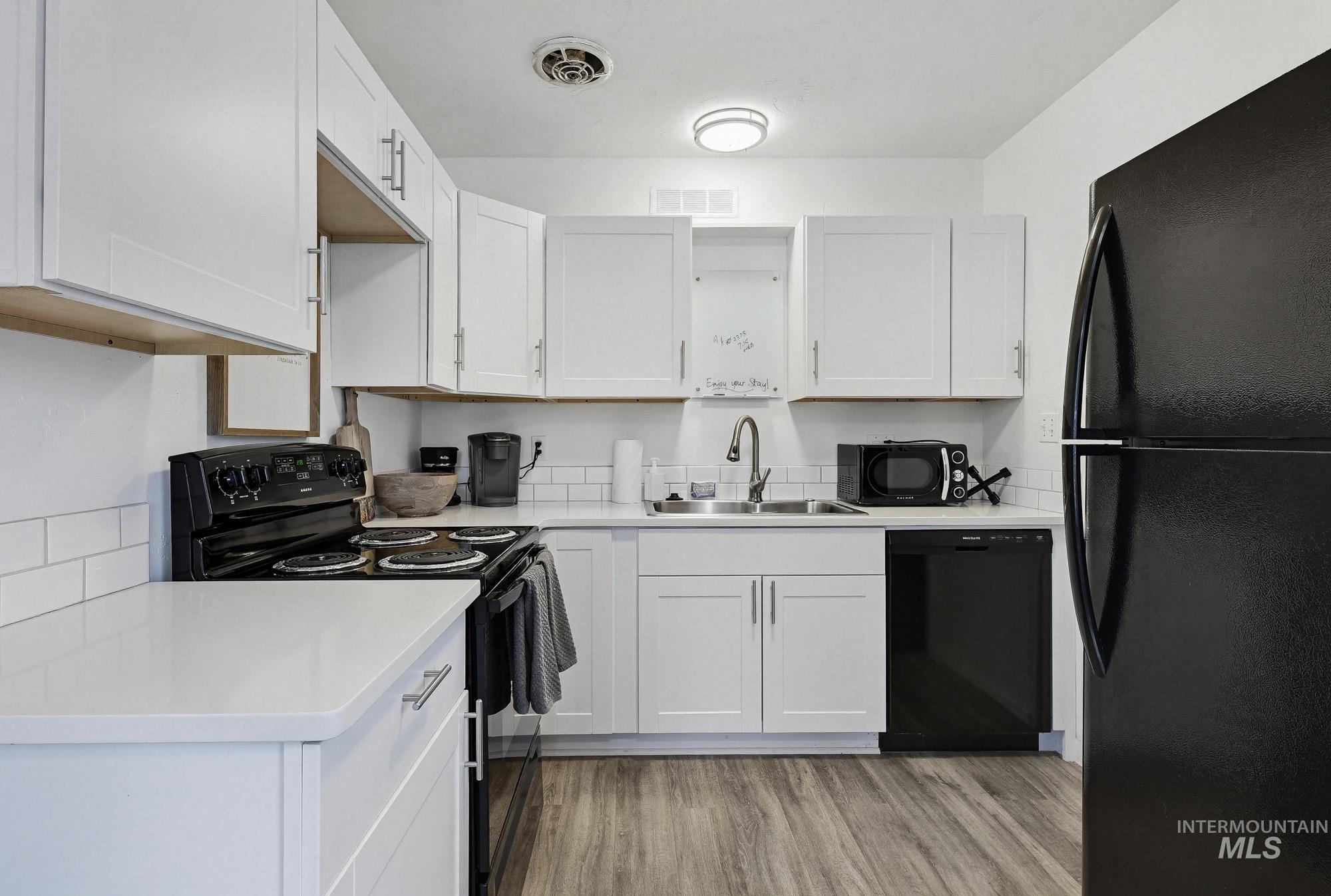2104 North 18th Street Boise, ID 83702 - Photo 8 of 19 Kitchen with black appliances, white cabinets, and light wood-style flooring