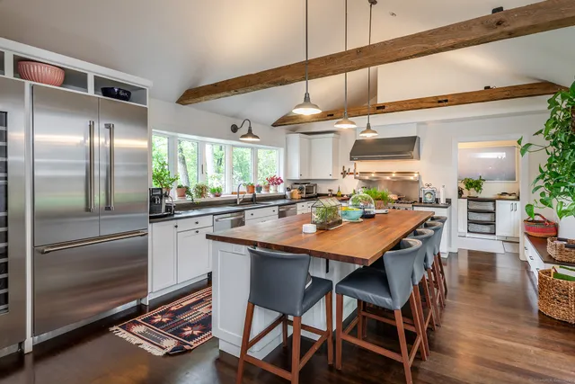 a kitchen with stainless steel appliances kitchen island granite countertop a table chairs and a refrigerator
