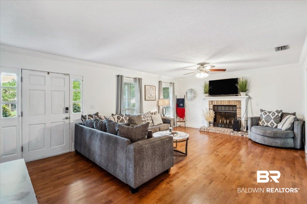 3616 Vista Ridge Drive Mobile, AL 36693 - Photo 2 of 20 Living room with crown molding, dark hardwood / wood-style flooring, a textured ceiling, a brick fireplace, and ceiling fan