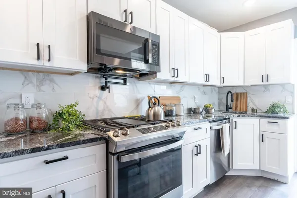 a kitchen with stainless steel appliances granite countertop a stove a sink and a microwave