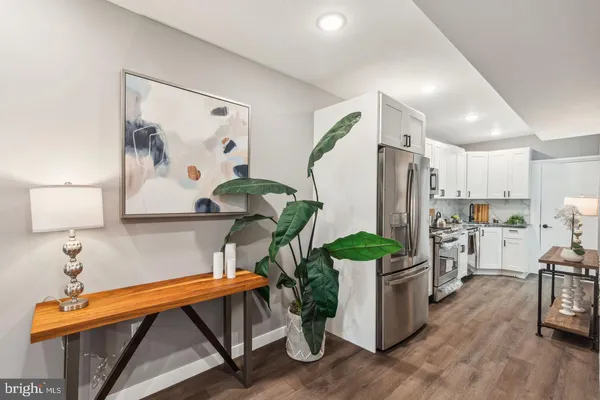 a kitchen with stainless steel appliances kitchen island granite countertop a refrigerator a stove a sink and white cabinets with wooden floor