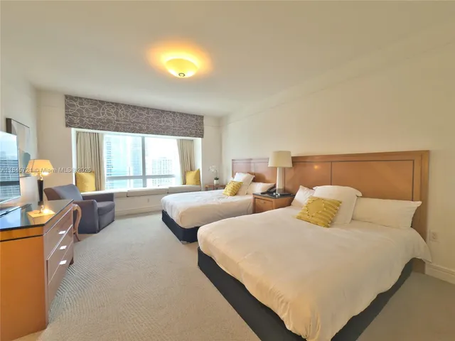 a bedroom with two beds and a large window