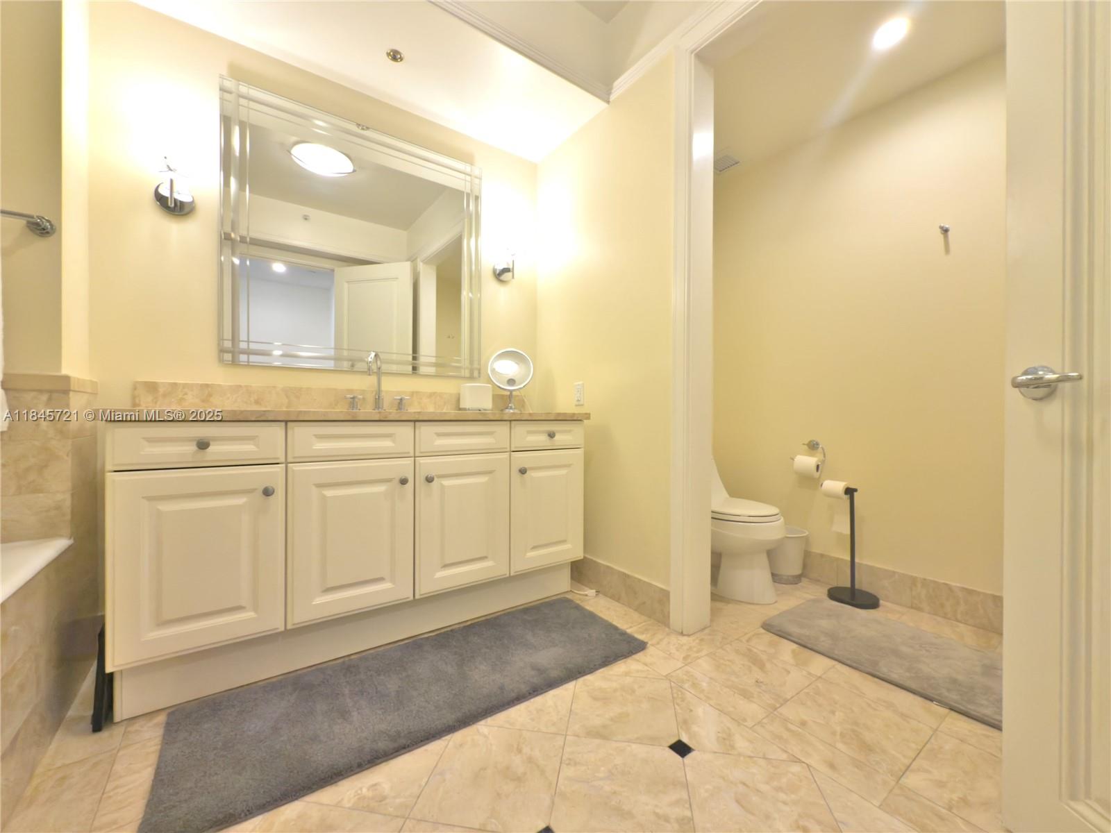 1435 Brickell Avenue, Unit 3412 Miami, FL 33131 - Photo 29 of 44 a spacious bathroom with a sink a toilet and a mirror