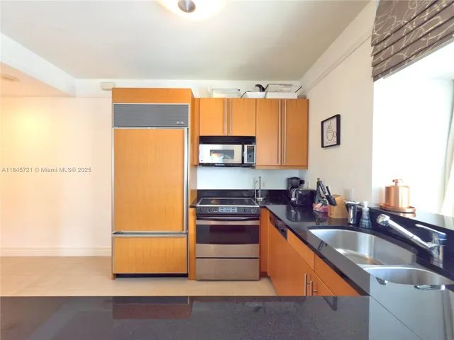 a kitchen with granite countertop a sink and a refrigerator