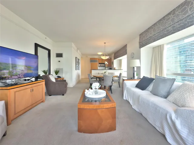 a living room with furniture kitchen view and a large window