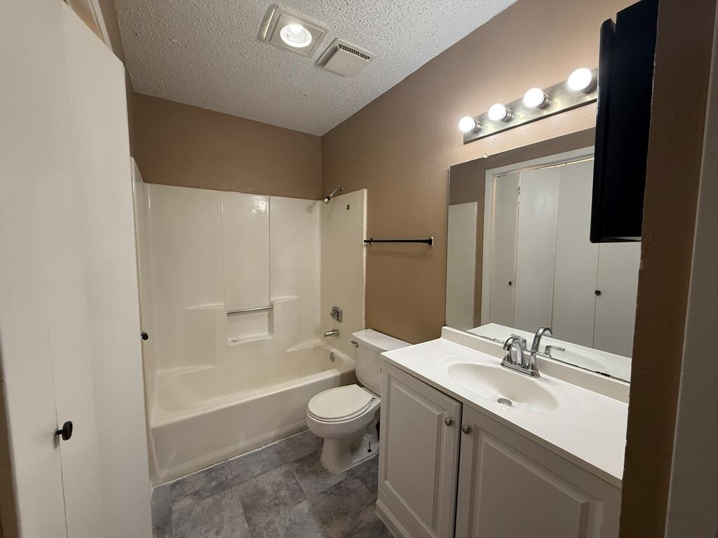 9696 Walnut Street, Unit 606 Dallas, TX 75243 - Photo 14 of 17 a bathroom with a granite countertop sink toilet a large mirror a bathtub and shower