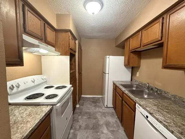 a kitchen with granite countertop a sink stove and refrigerator