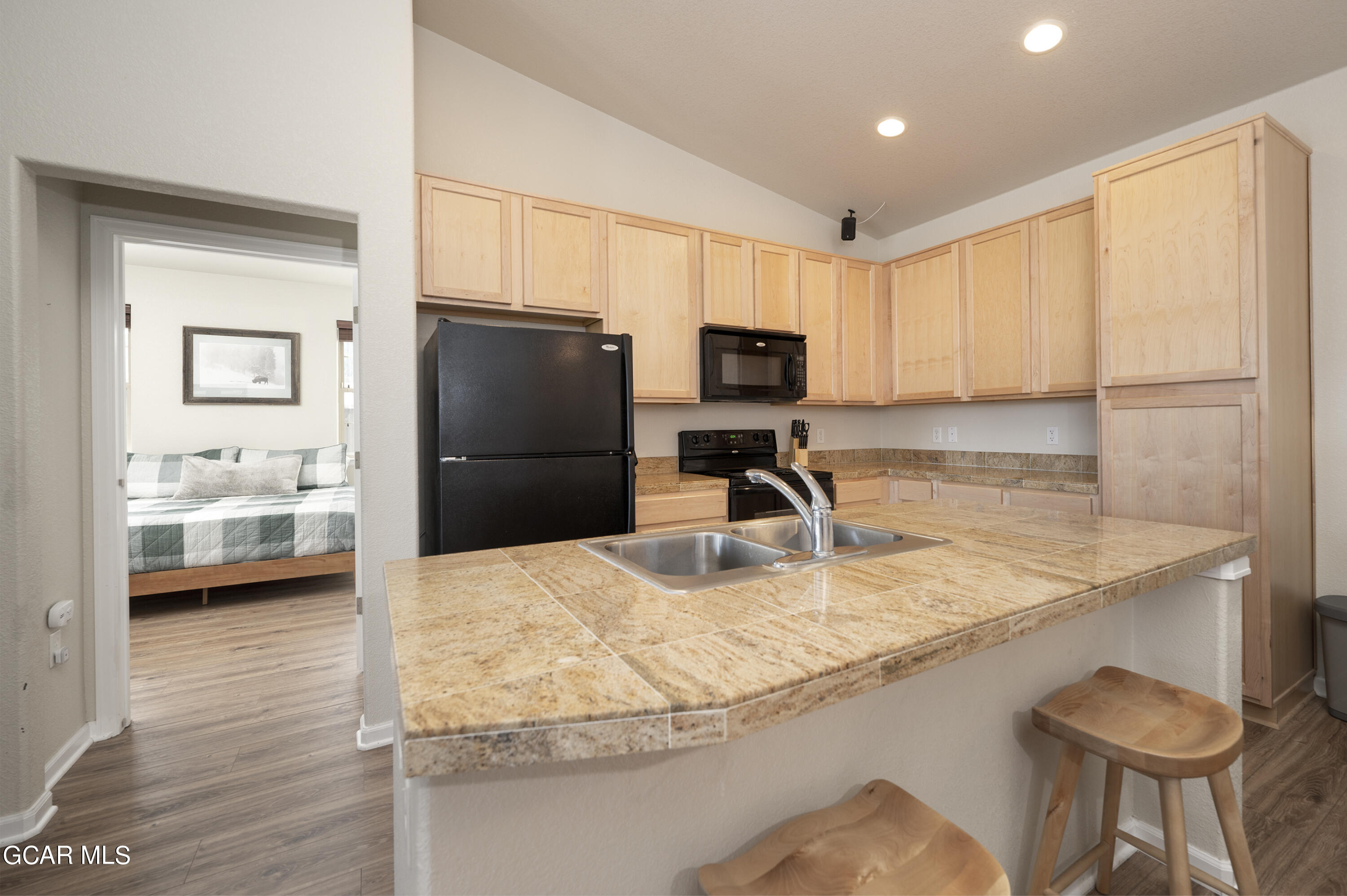 152 Village Road, Unit B306 Granby, CO 80446 - Photo 4 of 32 a kitchen with granite countertop a refrigerator a stove and a sink with wooden floor