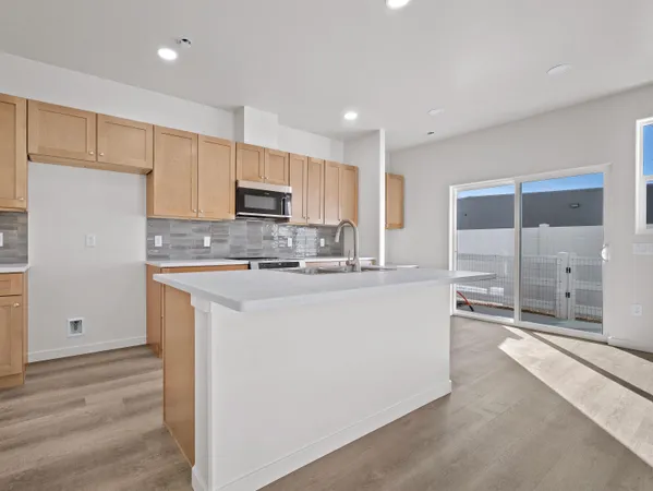 a kitchen with kitchen island granite countertop a sink a stove a refrigerator and white cabinets