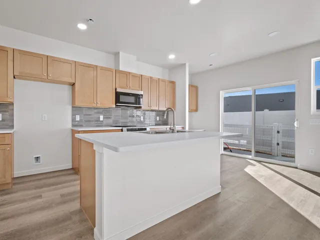 a kitchen with kitchen island granite countertop a sink a stove a refrigerator and white cabinets