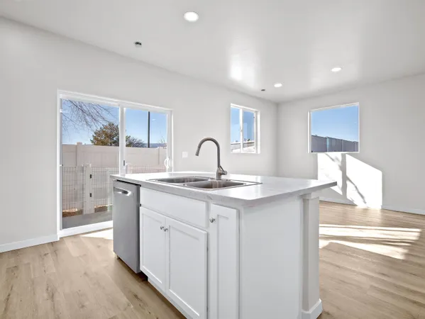 a kitchen with a sink wooden floor and stainless steel appliances