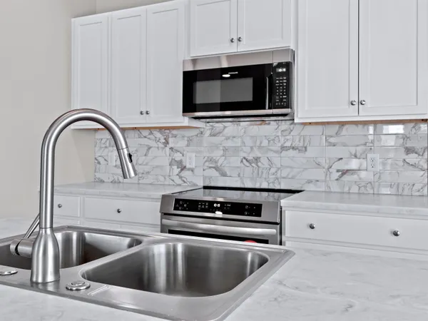 a kitchen with kitchen island granite countertop a sink cabinets and stainless steel appliances