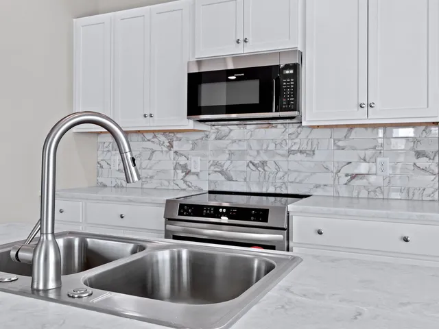 a kitchen with kitchen island granite countertop a sink cabinets and stainless steel appliances