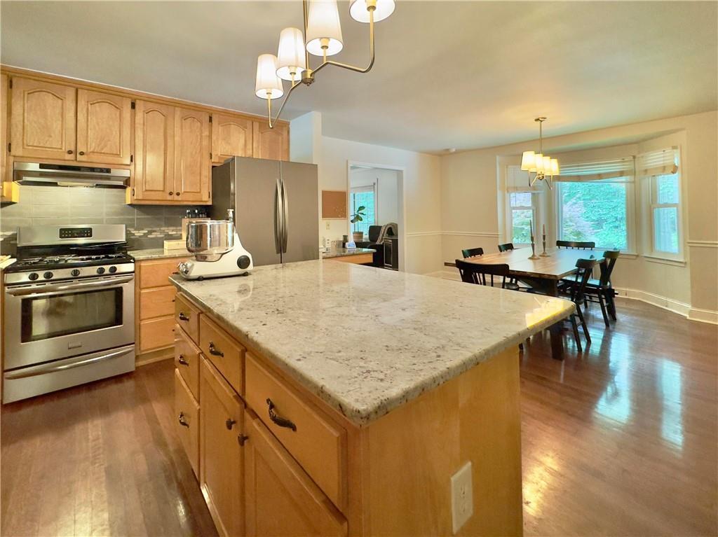 90 Howard Road Senoia, GA 30276 - Photo 50 of 73 a kitchen with stainless steel appliances granite countertop a stove refrigerator a dining table and chairs with wooden floor