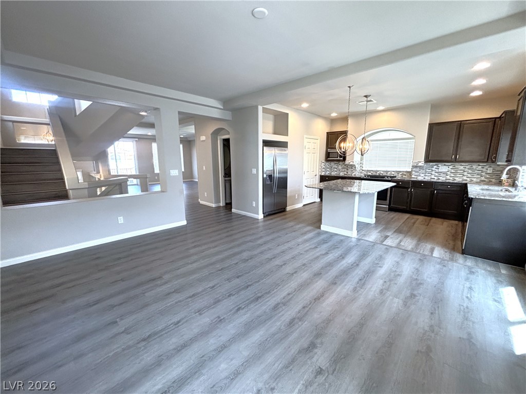 6425 Jackson Spring Road Las Vegas, NV 89118 - Photo 12 of 31 An open-concept living space connects a kitchen with an island and durable plank flooring.