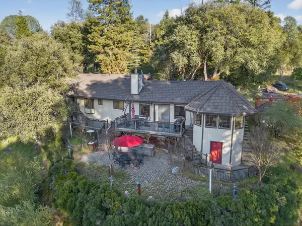 a view of a big house with a big yard plants and large trees