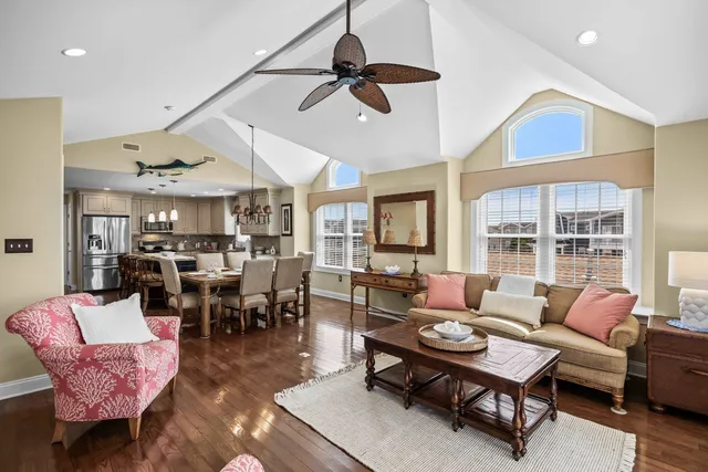 a living room with lots of furniture kitchen view and a chandelier