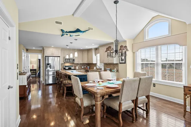a view of a dining room and livingroom with furniture wooden floor a chandelier