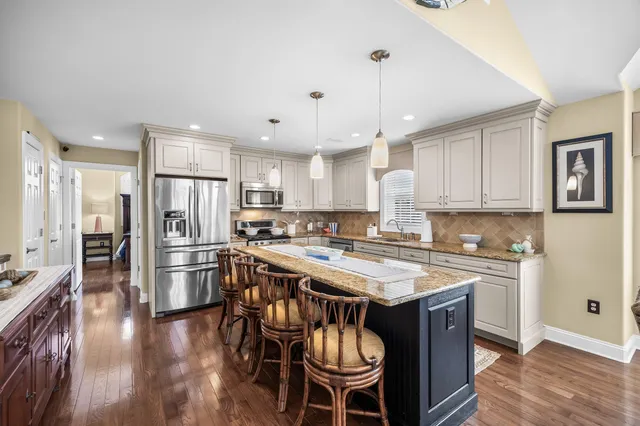 a kitchen with stainless steel appliances a stove a sink a refrigerator and chairs
