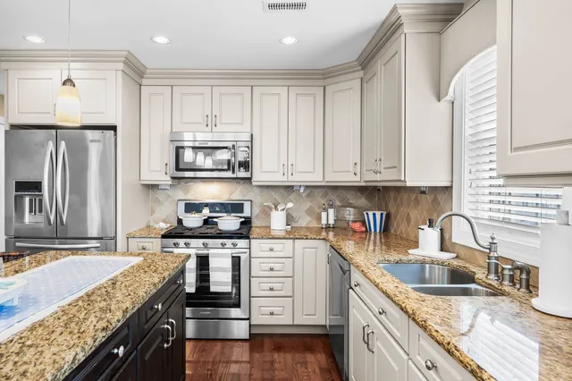 a kitchen with stainless steel appliances granite countertop a stove top oven a sink dishwasher a refrigerator and cabinets with wooden floor