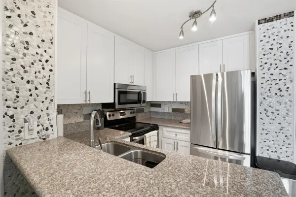 a kitchen with stainless steel appliances granite countertop a refrigerator a stove and a sink with wooden floor