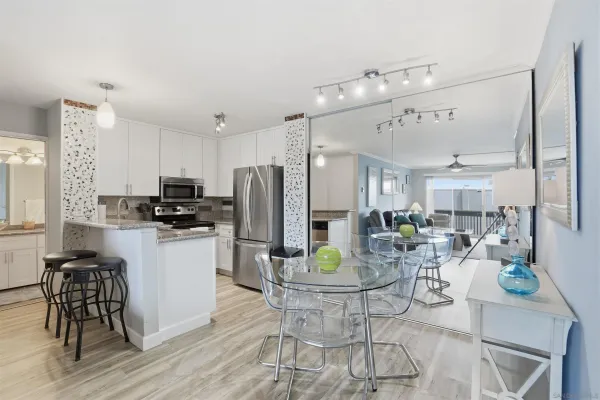 a kitchen with stainless steel appliances a dining table chairs stove refrigerator and cabinets