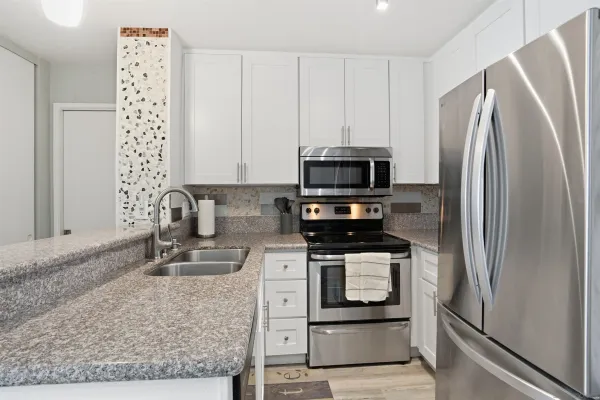 a kitchen with stainless steel appliances granite countertop a refrigerator a stove and a sink